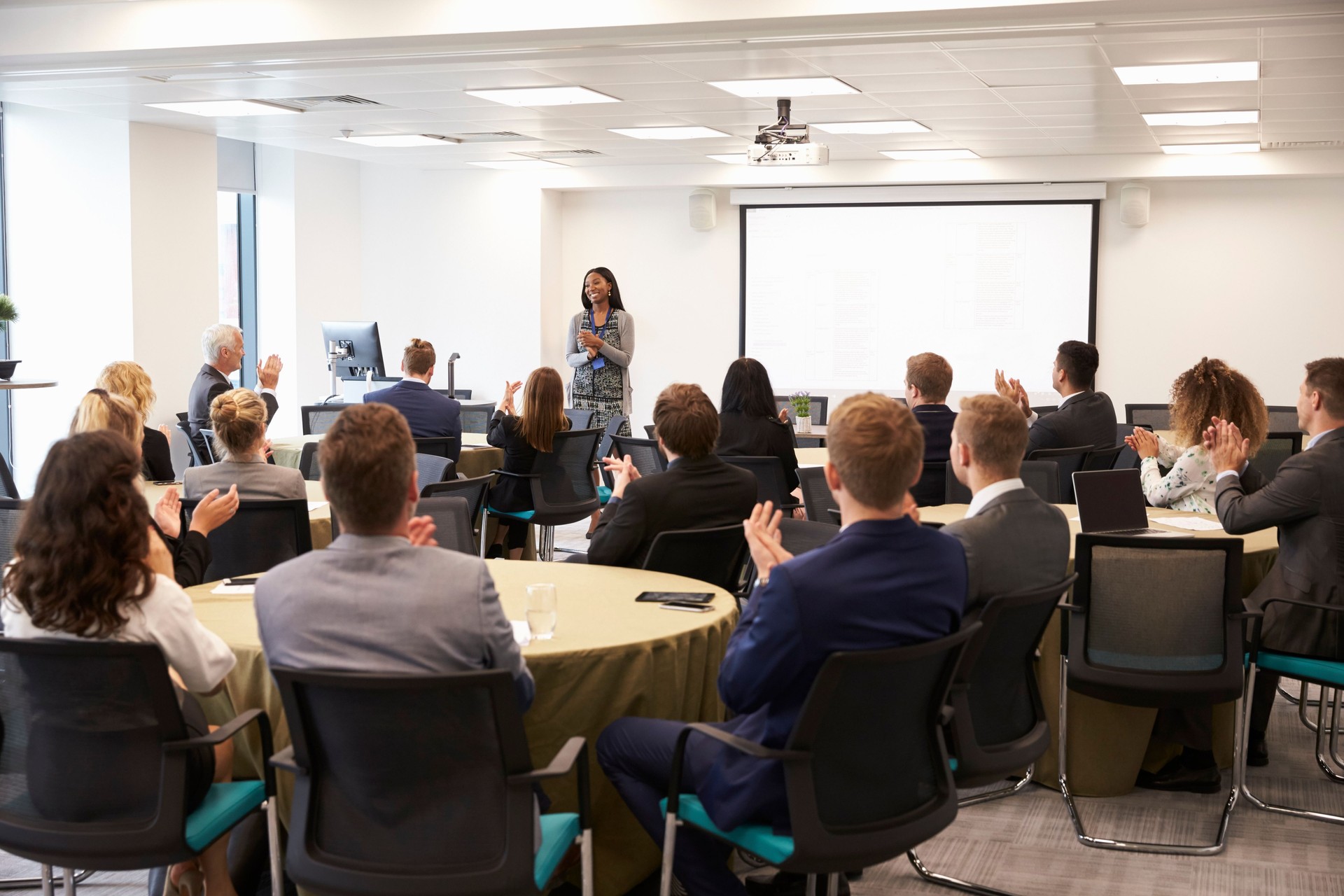 Delegates Applauding Businesswoman Making Presentation