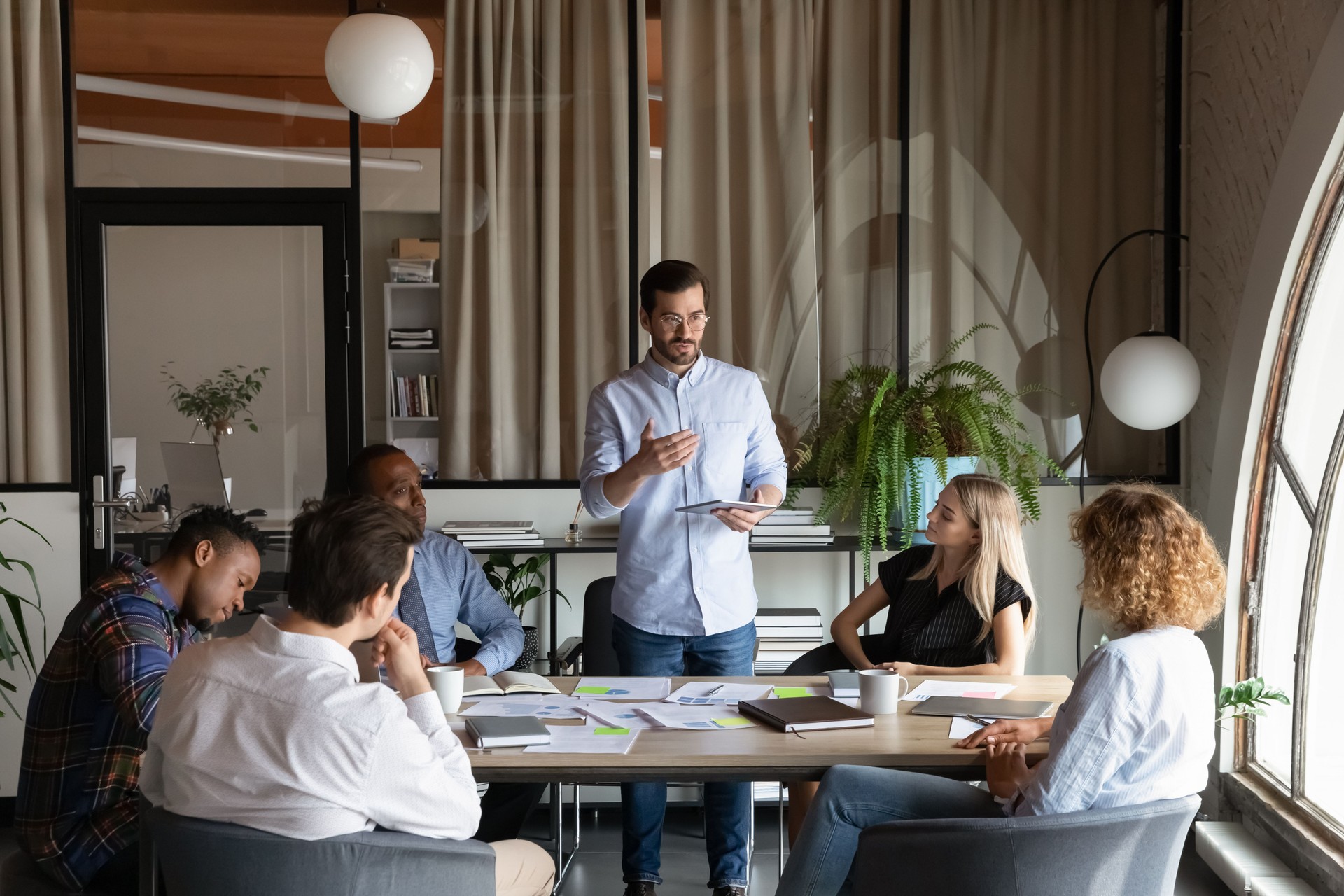 Confident business team leader speaking to employees at corporate meeting